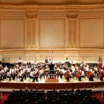 An orchestra playing in the stage of the Carniege hall linked to honors performance series at carnegie hall