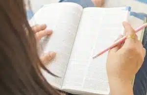 a woman holding a pencil checking the dictionary