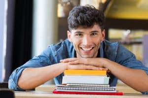 a male student smiling at the camera while holding his books
