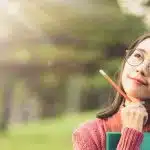 Young woman holding a pencil while thinking.