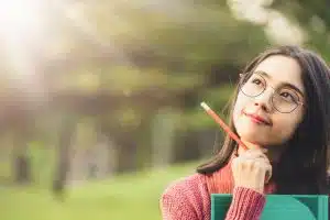 Young woman holding a pencil while thinking.