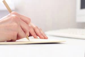 Image of a hand holding a pen and writing on a paper