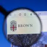 Brown University website viewed through a magnifying glass, emphasizing the importance of checking and meeting the Brown University application deadline.