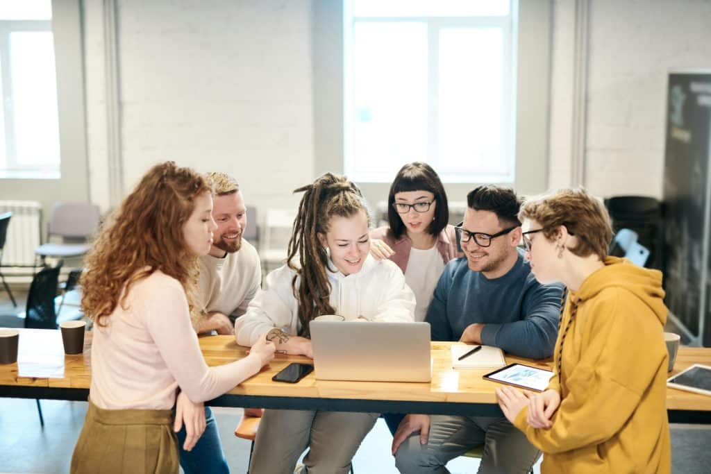 A group of students huddled in front of a laptop