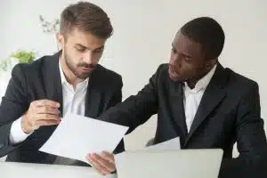 Two men discussing the documents they are holding