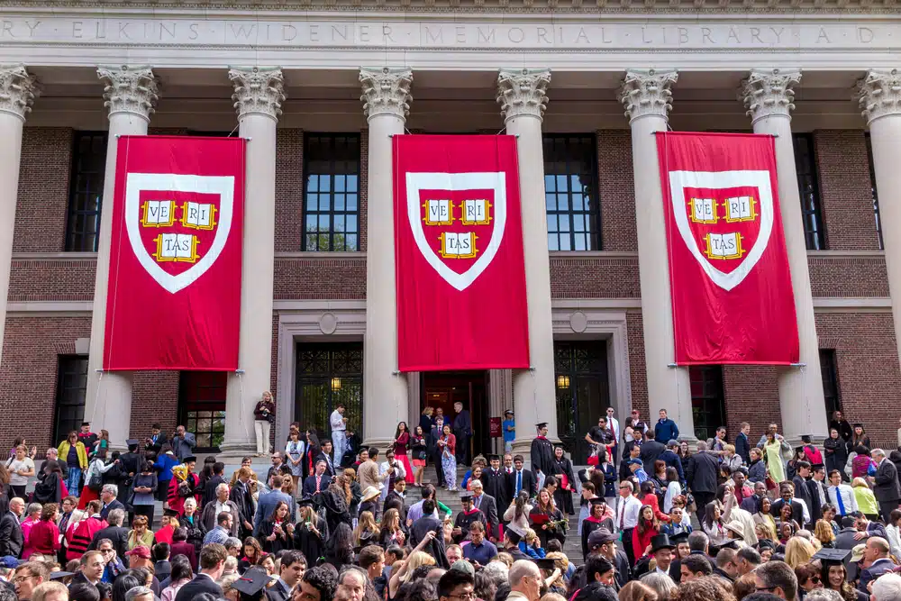Harvard students gathered by the stairs in front of a college building