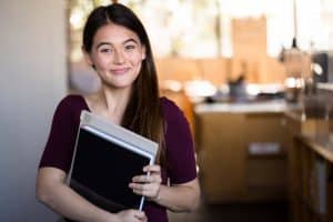 A female college student outside of classroom smiling for the camera