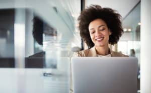 A woman smiling while looking at her laptop