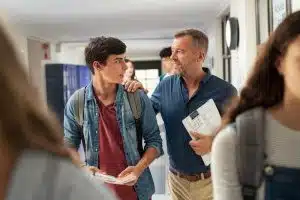 A professor talking to a student while they walk outside the classroom