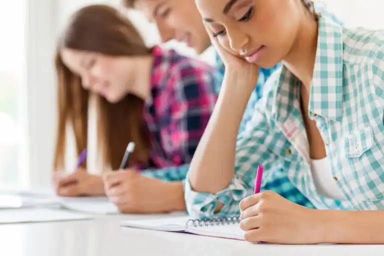 Row of students writing on their notebooks