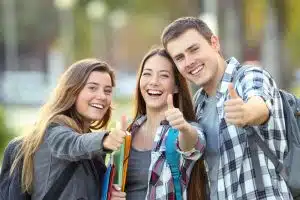 Three students smiling and doing the thumbs up sign