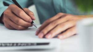 Unidentified person writing on a piece of paper.