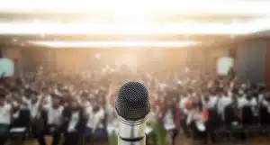 A microphone on stage situated in front of a crowd.