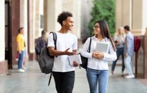 Two college students are walking in campus and talking.