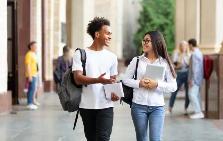 Two college students are walking in campus and talking.