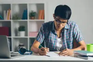 A male college student doing homework at home.