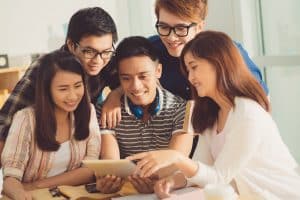 Five students are gathered to watch on a digital tablet.