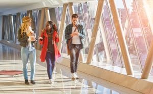 Three students walking with coffees while chatting.