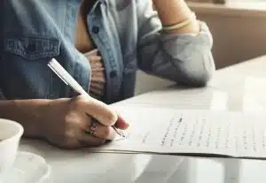 A woman writing a letter on a paper.