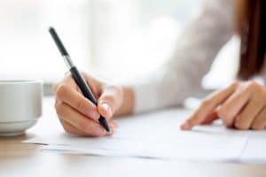 A person having a cup of coffee while writing.