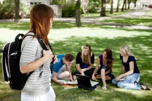 A group of university students studying together with one student standing in the foreground.