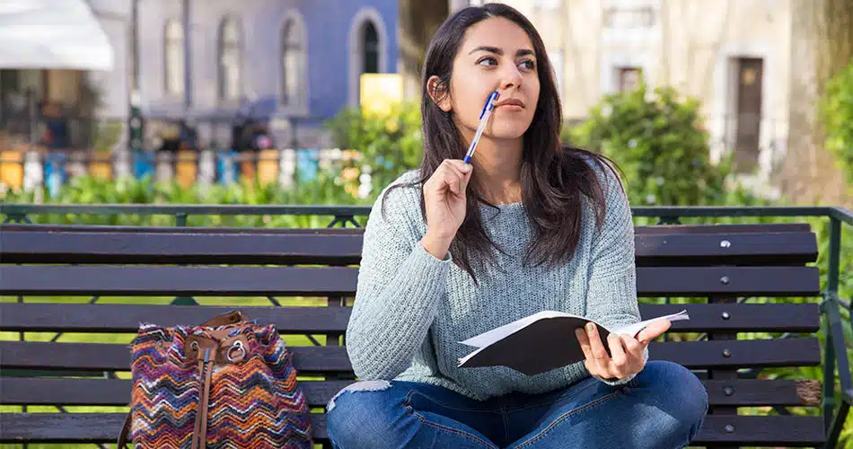 Female student writing on a bench.