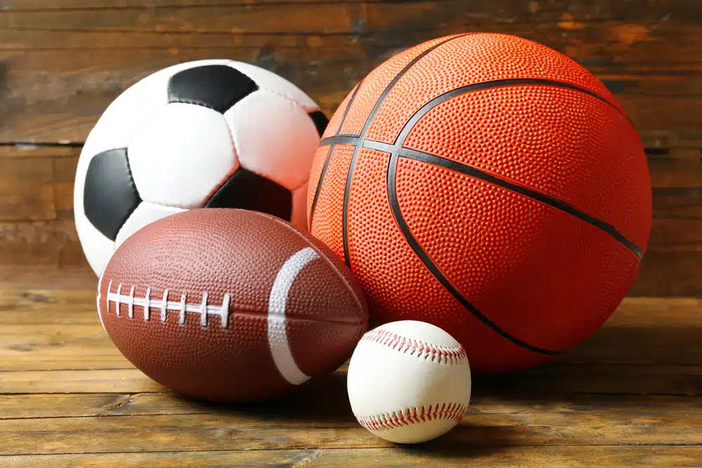 Four types of sports balls on wooden background.