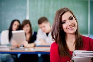 Female student smiling in the camera while in the classroom.