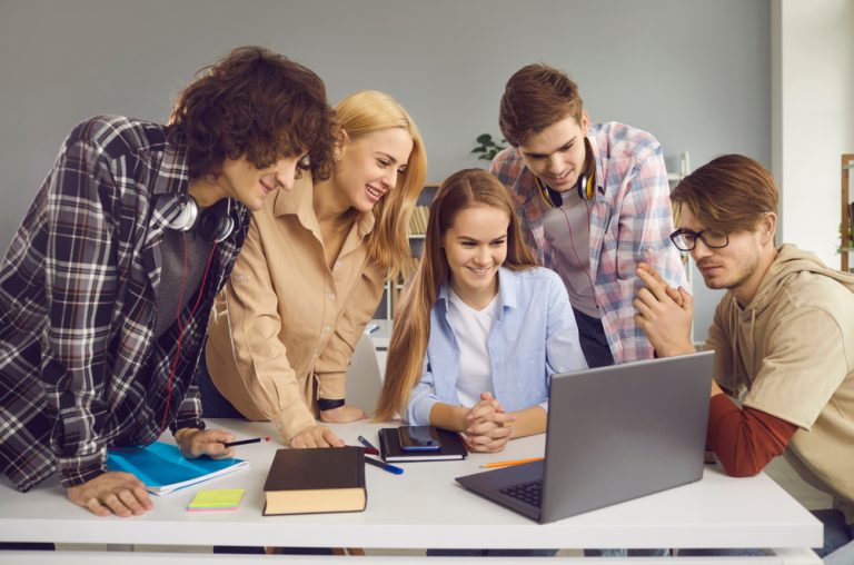 Male and female students looking at the screen of a laptop computer in class.