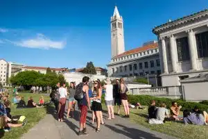 Students at the University of California Berkeley campus enjoying a warm day outdoors on the grass.