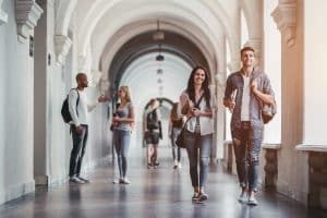 College students are walking in university hallway during break and communicating with each other.