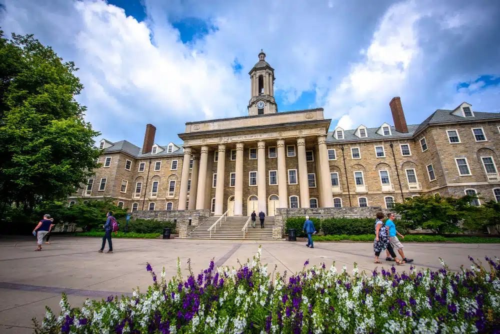 Penn State University's front side showing its buildings and some students walking by.