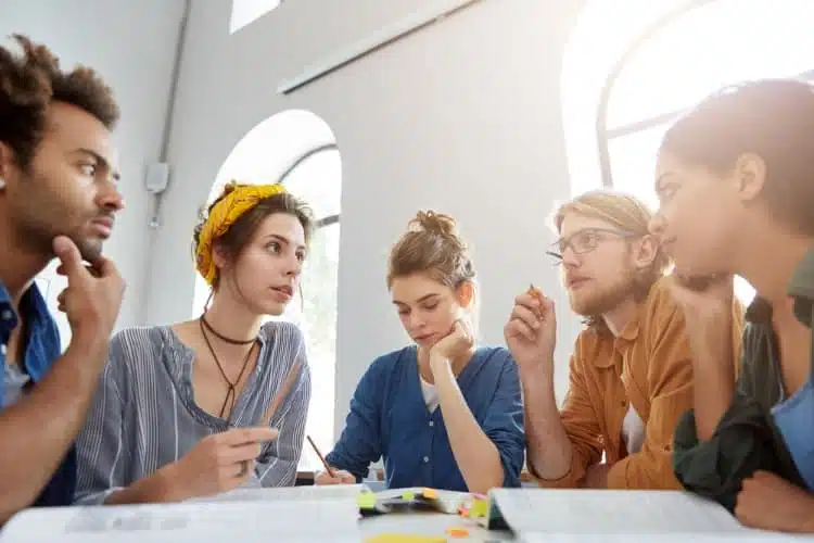 Students gathered around a table and talking.