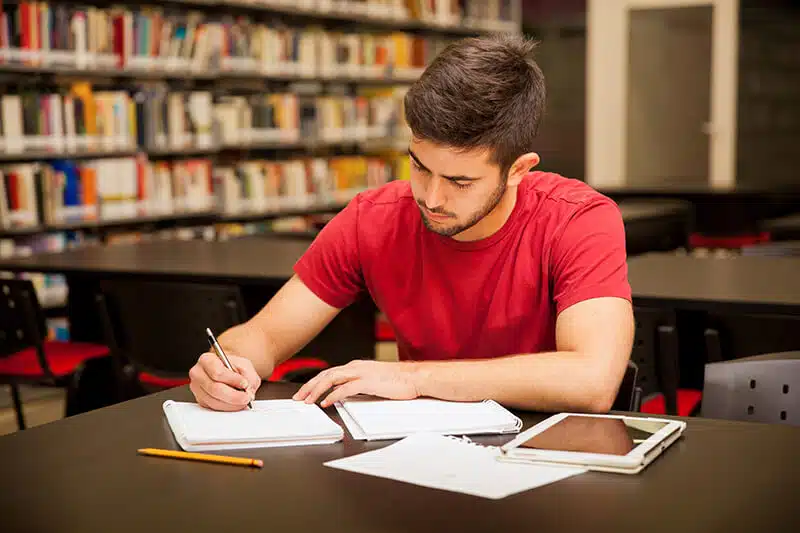 Young male studying in a library.