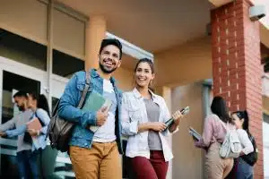 University students looking happy while standing outside of the main entrance