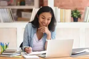 Young woman looking at a laptop while smiling.