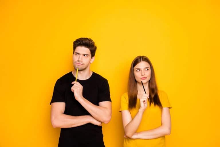 Two students thinking of something while leaning on a yellow wall.