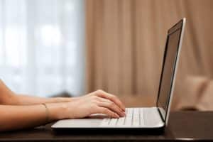 Using a laptop to type in a table.