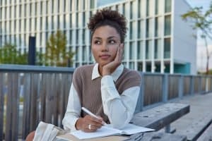 Female student holding a pen while looking distracted.