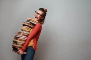 Young woman taking out lots of books while smiling for the camera.