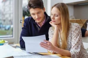 Two people reading a likely letter in a table.