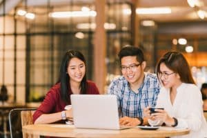 Three asian students looking at a laptop.