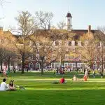 Students relax on the campus lawn in front of a historic building, reflecting the choice between UIUC vs Northeastern.