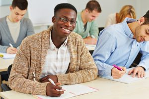 Male student answering an exam with his fellow classmates.