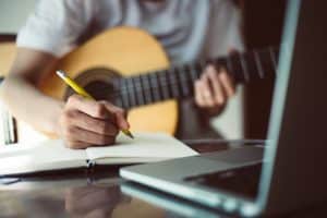 Male student writing a song using a paper.