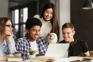 Group of students looking at a laptop in a table.