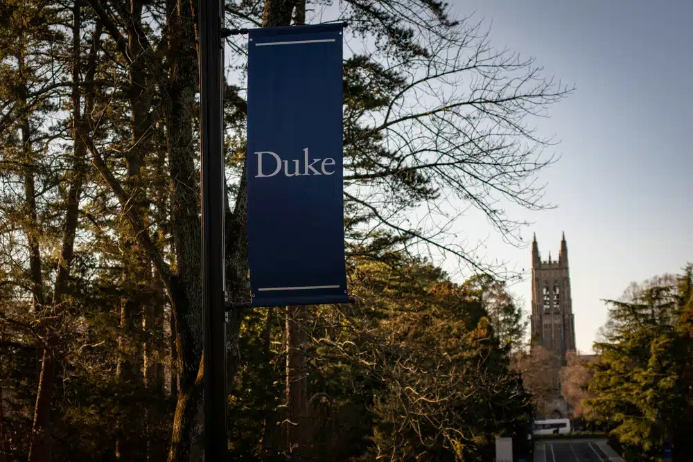 Duke banner placed on a trees near a walkway to Duke.