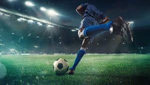 Unidentified man preparing to kick a ball in a football field.