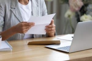 A woman opening a letter in a table.