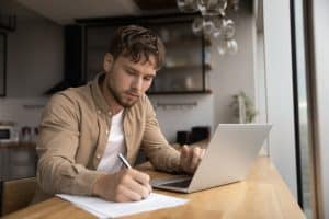 Young man writing in a desk while writing.